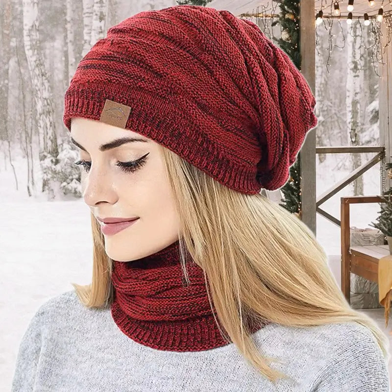 Frau trägt eine burgunderfarbene 2-in-1-Sturmhaube, die Kopf und Hals bedeckt und ideal für kalte Tage im verschneiten Wald ist.