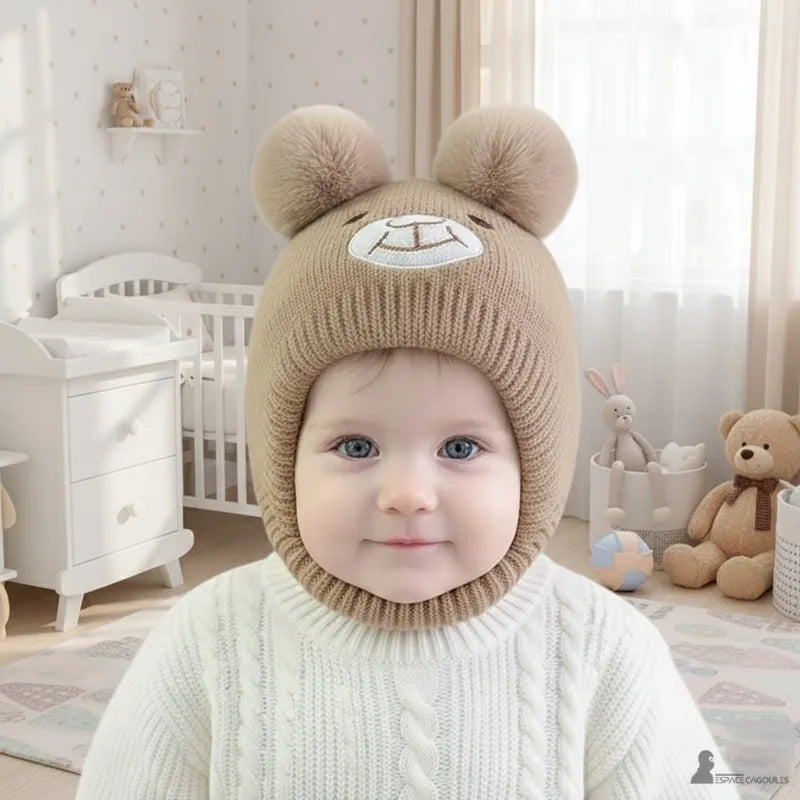 Bonnet Cagoule bébé marron porté par un nourrisson dans une chambre décorée avec doudous, bonnet tricoté chaud avec oreilles, Espace Cagoules