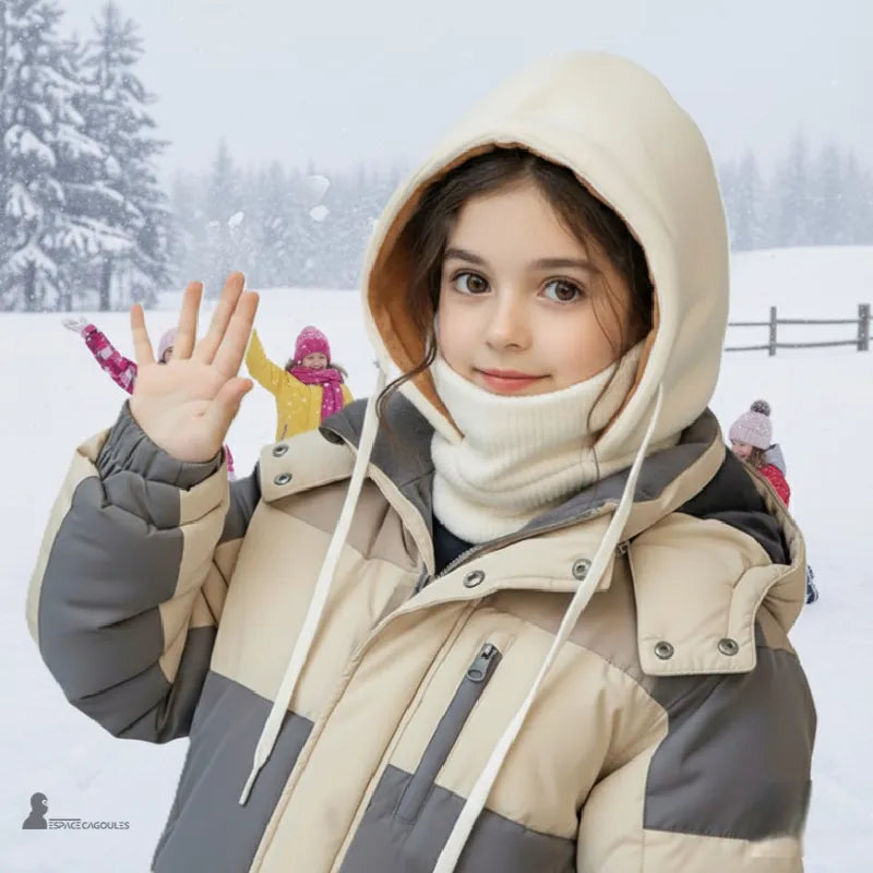 Bonnet cagoule enfant porté par une fillette en manteau beige jouant dans la neige avec fond de montagne hivernal - Espace Cagoules