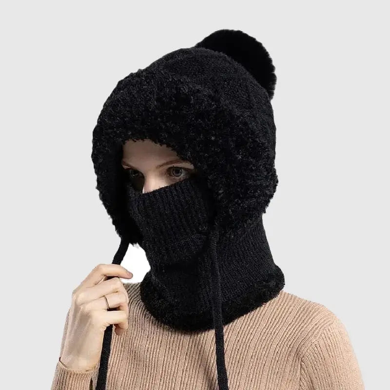 Femme portant un bonnet cagoule tricot noir avec doublure en fausse fourrure douce, pompon décoratif et cordons ajustables, idéal pour se protéger du froid en hiver.