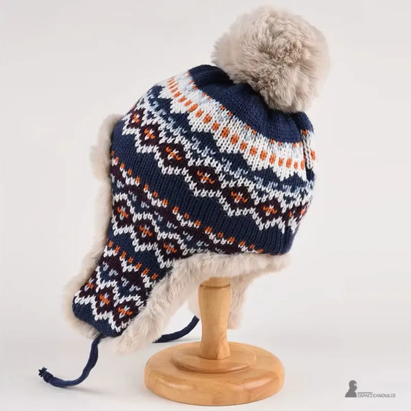 Blaue Chapka-Mütze von hinten gesehen, bunter Strick mit Bommel und warme Kunstfell-Innenseite