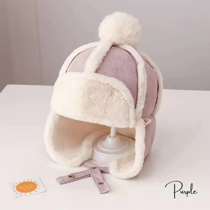 Children's Chapka beanie in purple and white fabric, with visible stitching and faux fur interior, placed on a white backing with a neutral background.