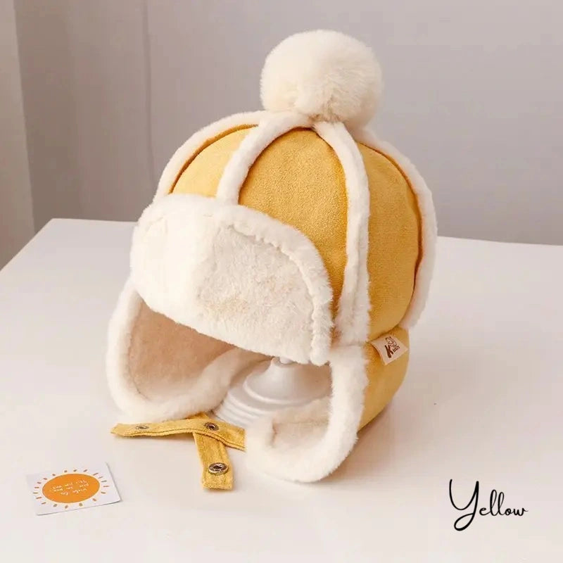 Yellow Children's Chapka Hat with white faux fur interior, wool pompom and adjustable ties, presented on a white backing with a neutral background.