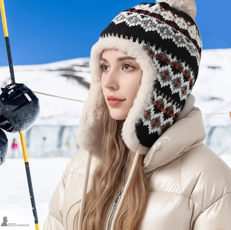 Schwarzer Chapka-Hut, der von einer Frau in den verschneiten Bergen getragen wird, Hut mit Bommel und rot-weißen Mustern