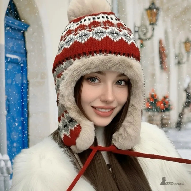 Rote Hapka-Mütze, die von einer Frau in einem weißen Mantel auf einer verschneiten Straße getragen wird, Strickmütze mit Bommel und Pelzfutter