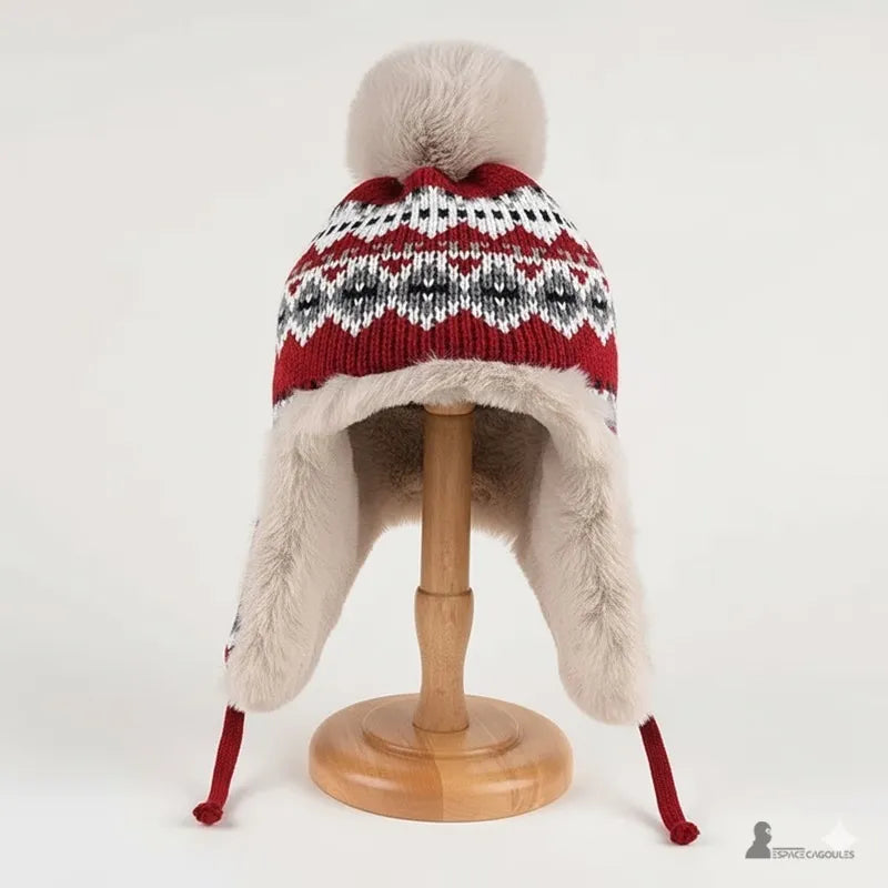 Rote Mütze von vorne gesehen, gestrickt in schwarz-weißen Mustern mit Bommel und warmem Kunstfell-Innenseite