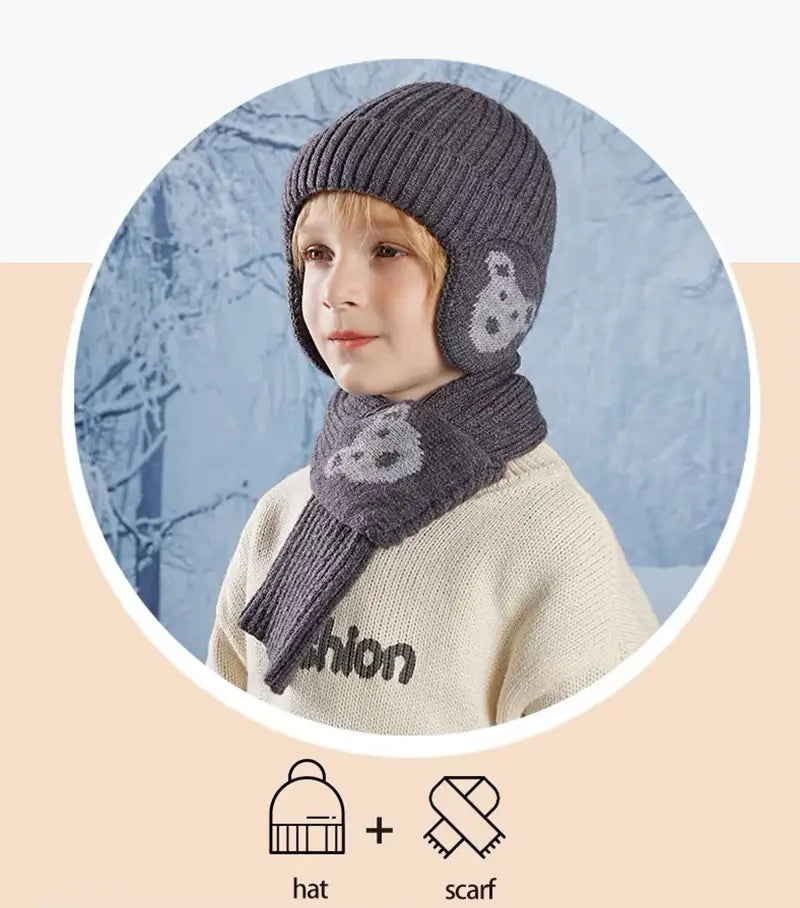 Garçon portant un ensemble bonnet écharpe enfant en tricot gris foncé avec des motifs d'ours, présenté dans un cadre circulaire avec un fond hivernal givré et des icÎnes indiquant l'association d'un bonnet et d'une écharpe.