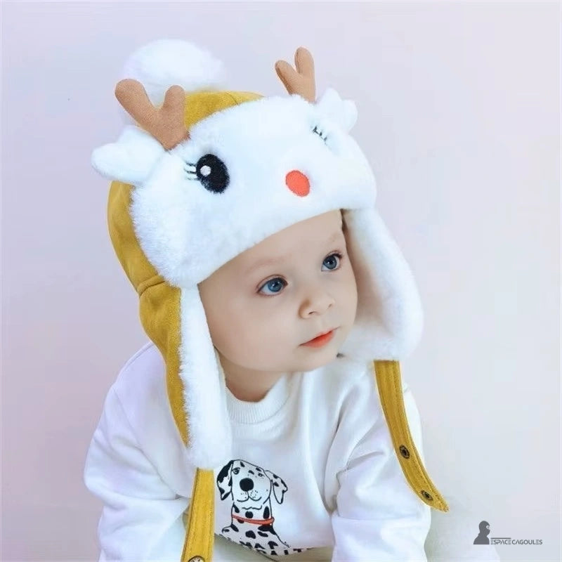 Yellow fleece reindeer children's hat with ears and white pompom worn by a blue-eyed baby indoors