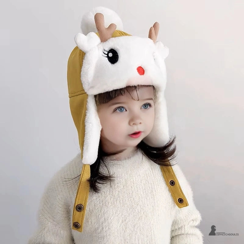 Yellow fleece reindeer hat with white pompom worn by a little girl with brown hair indoors