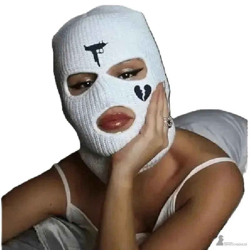 Cagoule 3 trous blanche portée par une femme, décorée avec motifs brodés noirs représentant une arme et un cœur brisé