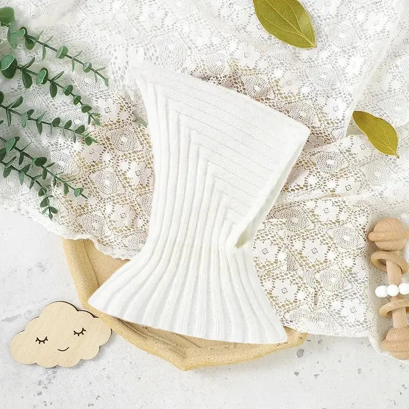 Weiße Strick-Sturmhaube für Babys, flach mit feinen Details und tailliertem Design, ideal, um Kleinkinder im Winter warm zu halten.