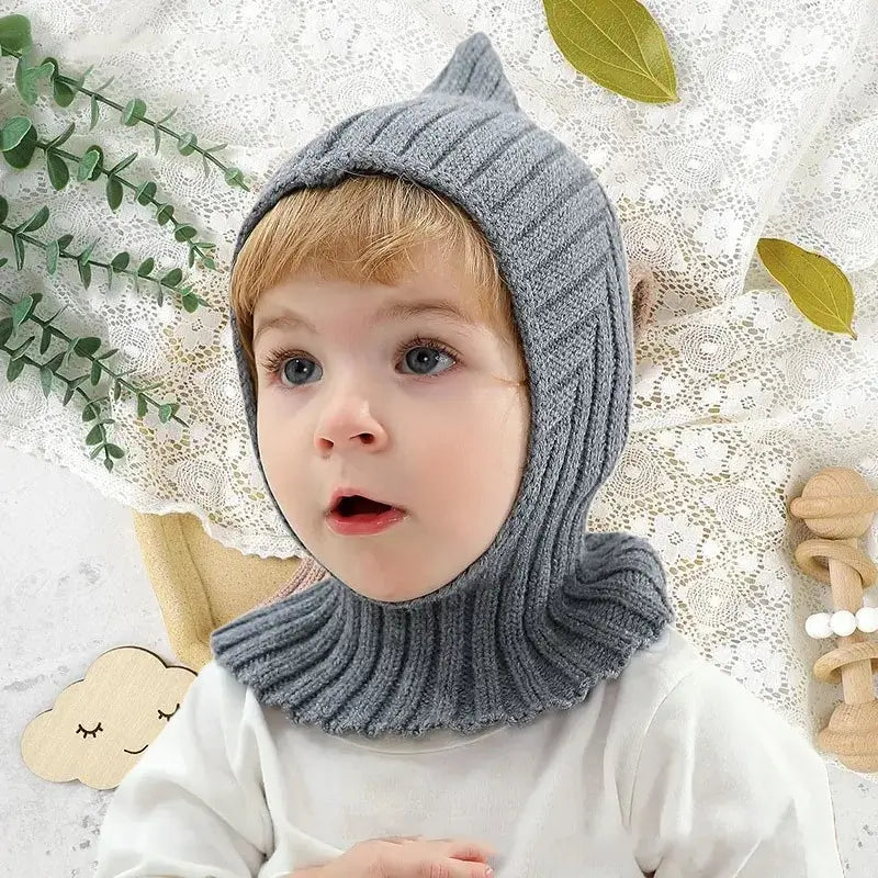 Das Baby trägt eine weiche, khakifarbene Sturmhaube aus Strick mit tailliertem Finish für optimalen Schutz vor Kälte. Baby-Sturmhaube für Winteraktivitäten.