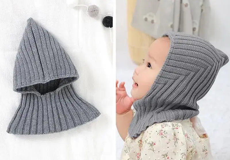 Das Baby trägt eine graue Stricksturmhaube, die Kopf und Hals bedeckt und perfekt für kalte Tage ist, während es bequem und trendy bleibt. Baby-Sturmhaube für den Winter geeignet.
