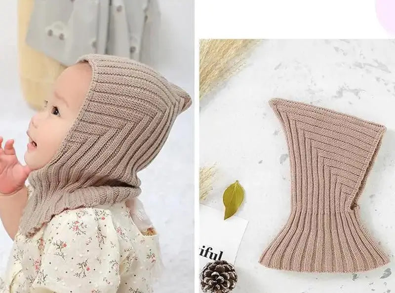 Das Baby trägt eine weiche, gestrickte khakifarbene Sturmhaube, die Schutz vor Kälte bietet, mit einem praktischen, taillierten Design für Outdoor-Aktivitäten. Elegante und warme Baby-Sturmhaube.