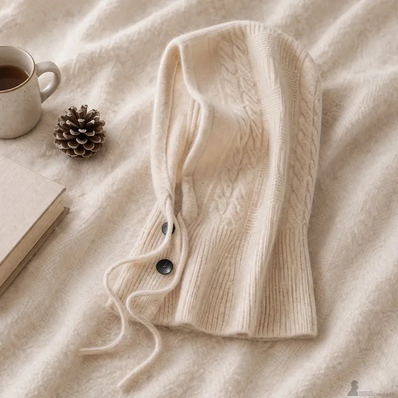 Cagoule en cachemire pour femme beige posée à plat sur plaid avec cordons et boutons visibles - Espace Cagoules