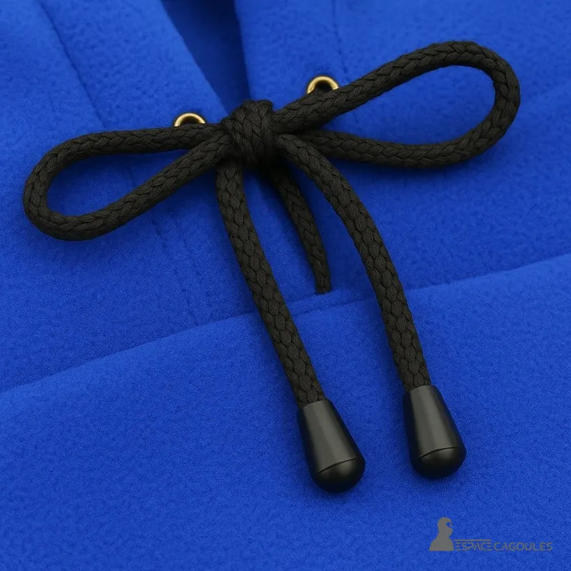 Cagoule Capuche bleue avec zoom sur les cordons noirs noués et œillets dorés, tissu polaire bien visible.