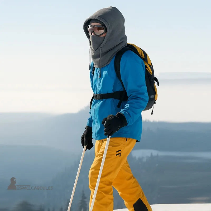 Grey hood worn by a skier with a blue jacket and yellow pants, in the middle of an ascent in the snowy mountains.