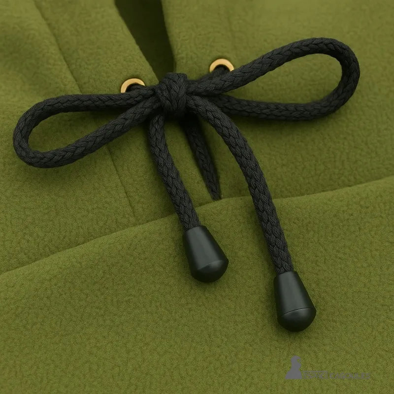 Cagoule Capuche Verte avec zoom sur les cordons noirs noués et œillets dorés, en tissu polaire doux.