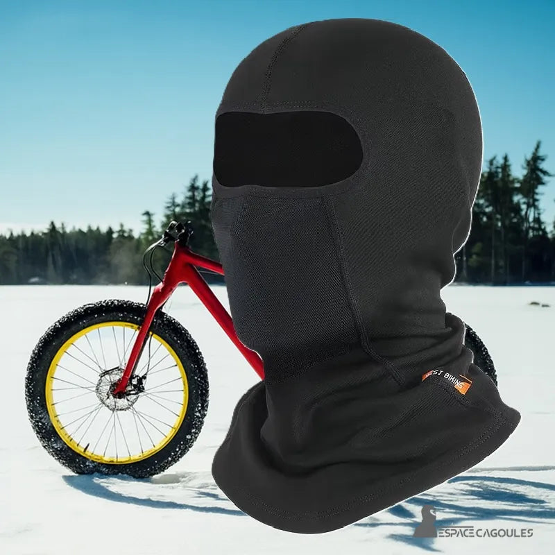 Cagoule cycliste noire en situation hivernale avec vélo sur fond enneigé