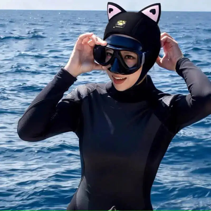 Diver in a neoprene suit wearing a humorous black diving hood with cat ears. Original accessory for scuba diving, suitable for wearing a mask.