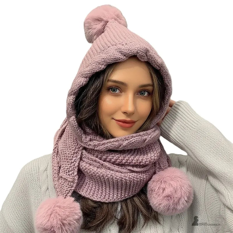 Cagoule écharpe rose clair tricotée avec pompons moelleux, femme portant un pull beige sur fond neutre, tenue d’hiver douce et élégante – Espace Cagoules