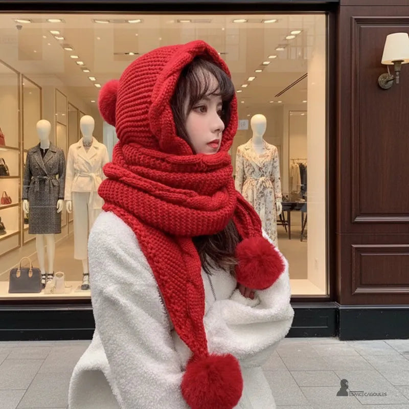 Cagoule écharpe rouge femme, maille tricotée épaisse avec pompons, portée en extérieur devant une vitrine de magasin – Espace Cagoules