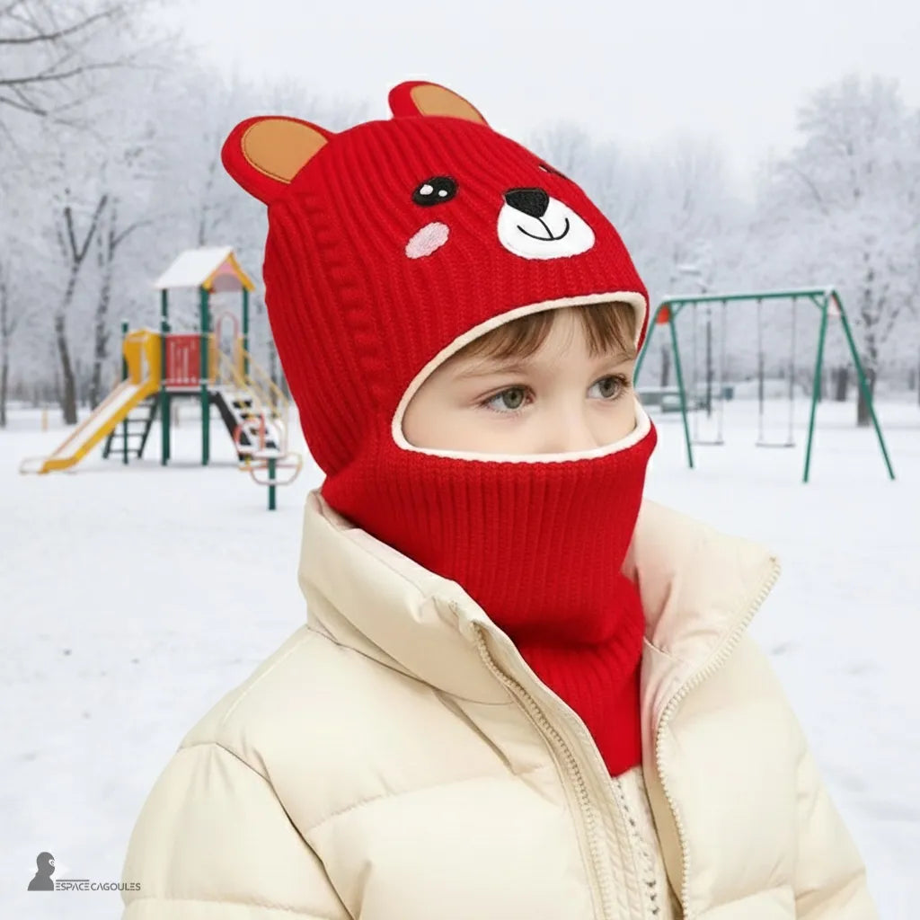 Passamontagna per bambini di 5 anni che indossano un passamontagna con orso rosso in un parco innevato con strutture da gioco sullo sfondo che offrono calore e supporto intorno al viso – Espace Cagoules