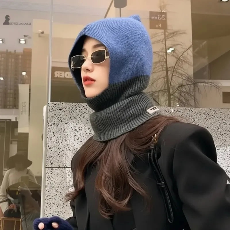 Dambalaklava i blått och grått ylle utomhus, sedd från sidan med figursydd huva och ståkrage för optimal värme