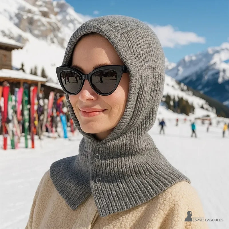 Cagoule Femme Grise portée par une femme avec lunettes sur fond de station de ski