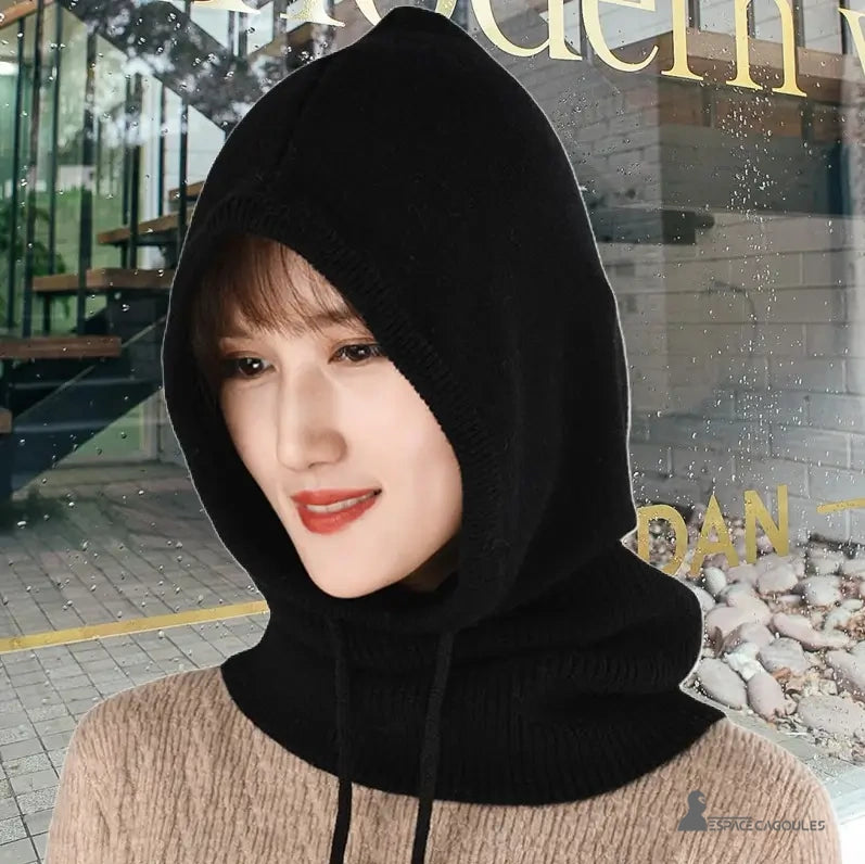 Black winter women's balaclava worn by a woman in front of an urban window