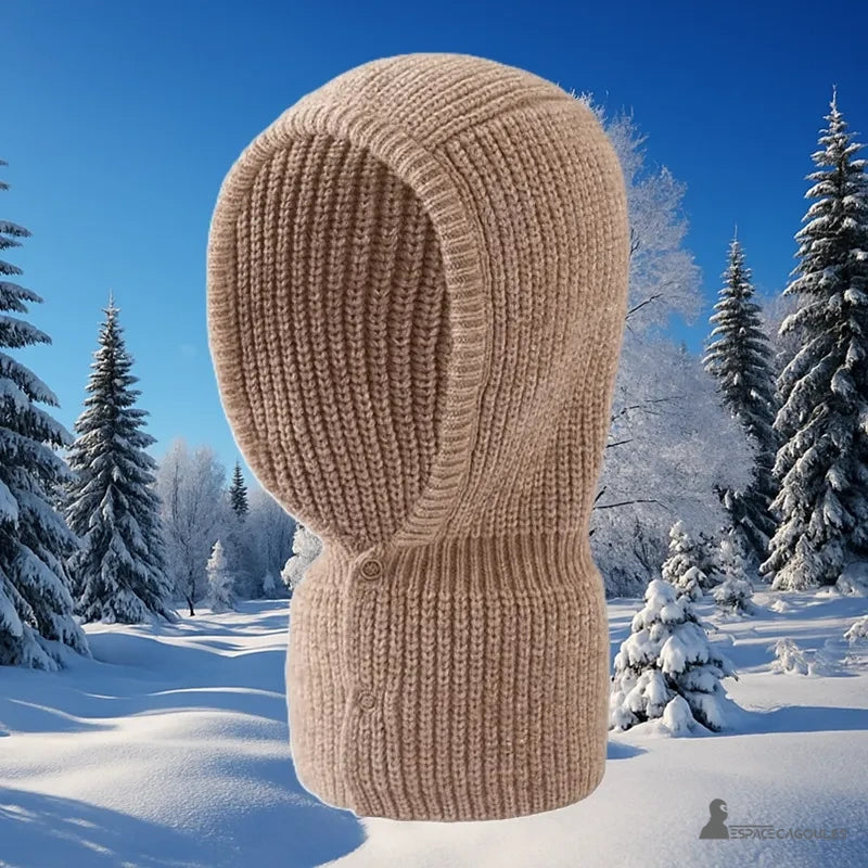 Cagoule Femme Maille beige épaisse présentée sur fond de paysage enneigé, idéale pour les sorties hivernales