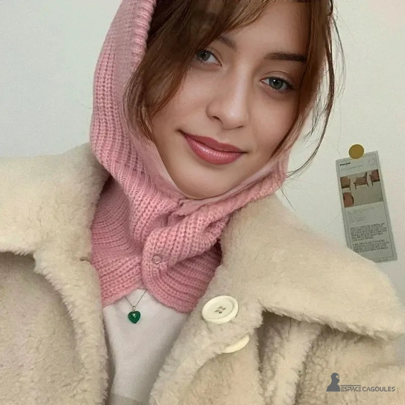 Cagoule Femme Rose portée par une femme souriante en intérieur, assortie à un manteau beige pour un look doux et hivernal