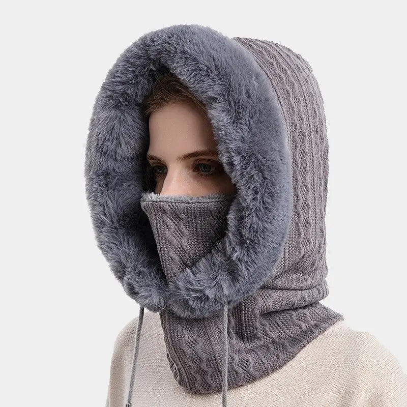 Cagoule femme fourrure grise avec tricot élégant et doublure en fausse fourrure moelleuse, offrant une protection chaude et confortable contre le froid hivernal.