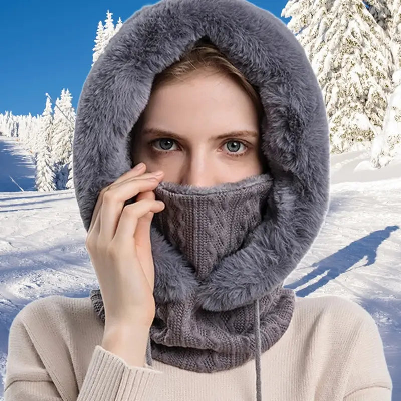 Cagoule femme fourrure grise avec doublure en fausse fourrure douce, portée dans un décor hivernal enneigé, offrant chaleur et confort pour les activités en plein air.