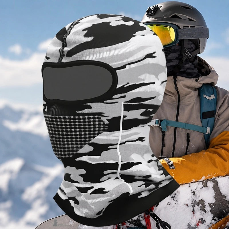 Cagoule fine sous casque de ski camouflage gris avec zone de respiration gaufrée, portée à côté d'un skieur en casque et masque en montagne enneigée - Espace Cagoules