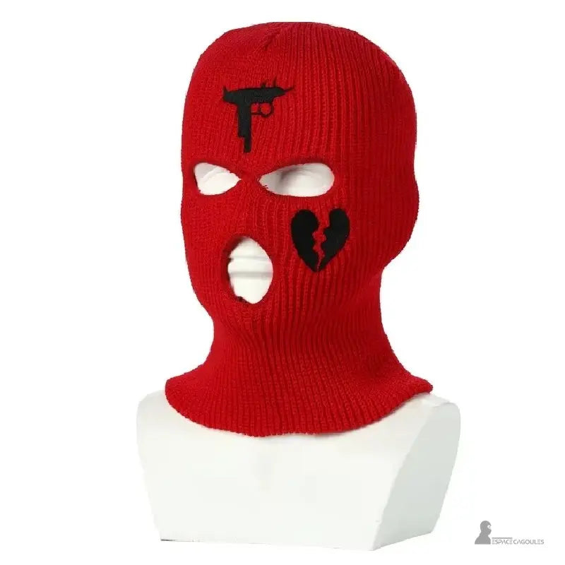 Cagoule gangster rouge éclatante en tricot avec broderies noires pistolet et cœur brisé, posée sur mannequin buste blanc