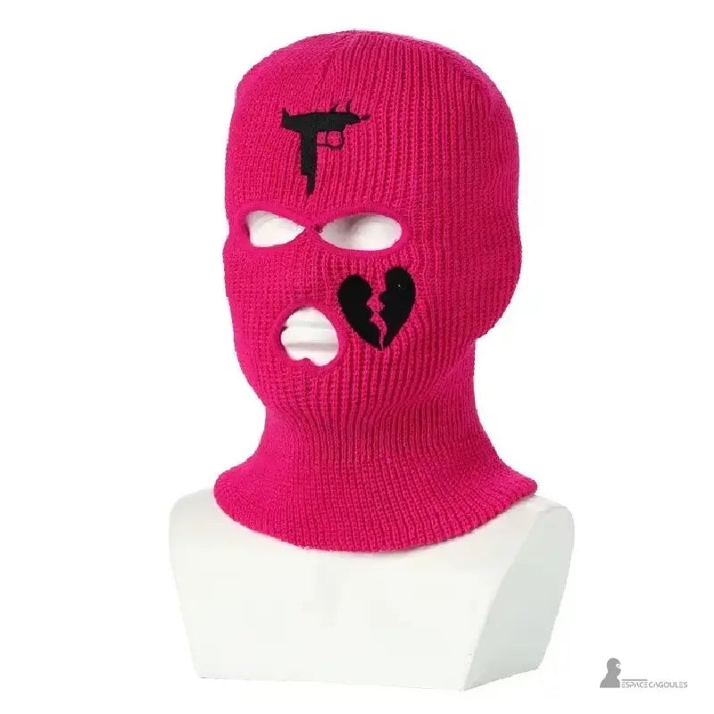 Passamontagna gangster rosso rosa appariscente lavorata con pistola nera e ricamo a cuore spezzato, esposta su un busto bianco