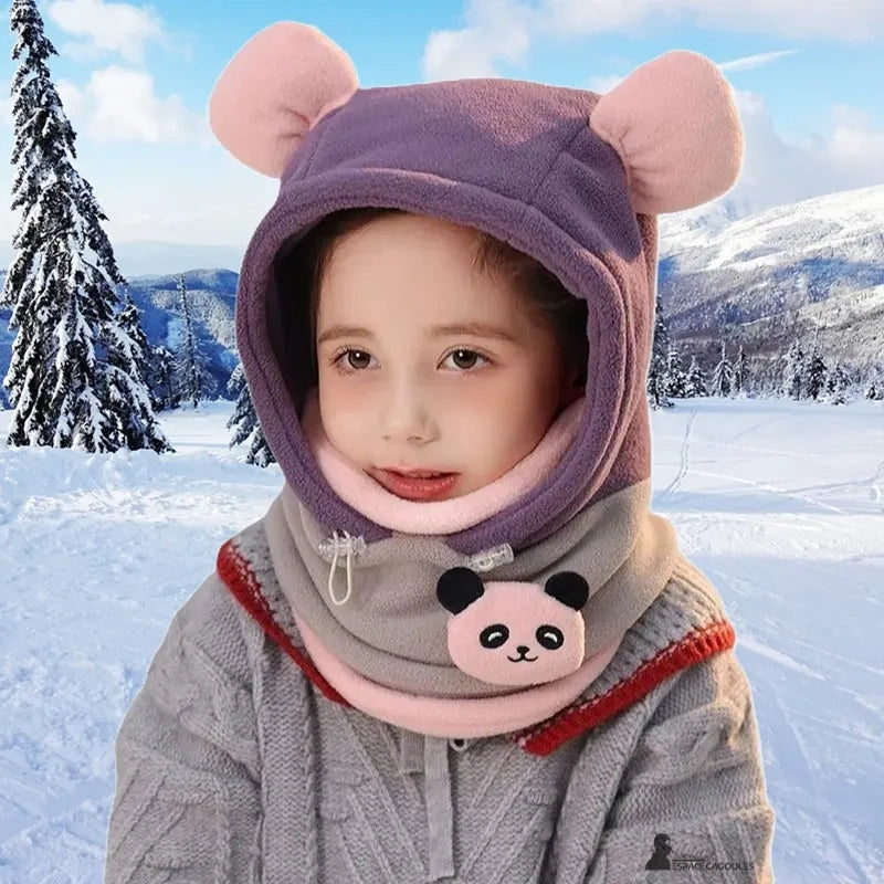 Purple and grey child's very cold balaclava with pink ears, panda décor, worn by a girl in front of a snowy mountain landscape.