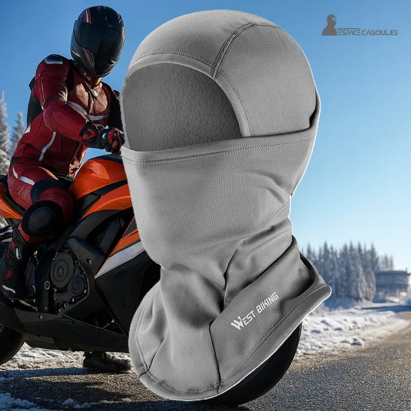 Wintersturmhaube für graues Motorrad auf Winterhintergrund mit Biker im roten Overall, der auf verschneiter Straße fährt