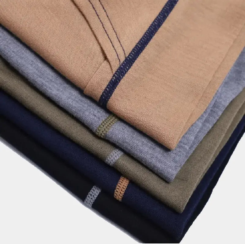 Collection de cagoules en laine mérinos soigneusement empilées, disponibles en plusieurs coloris pour affronter le froid avec style.