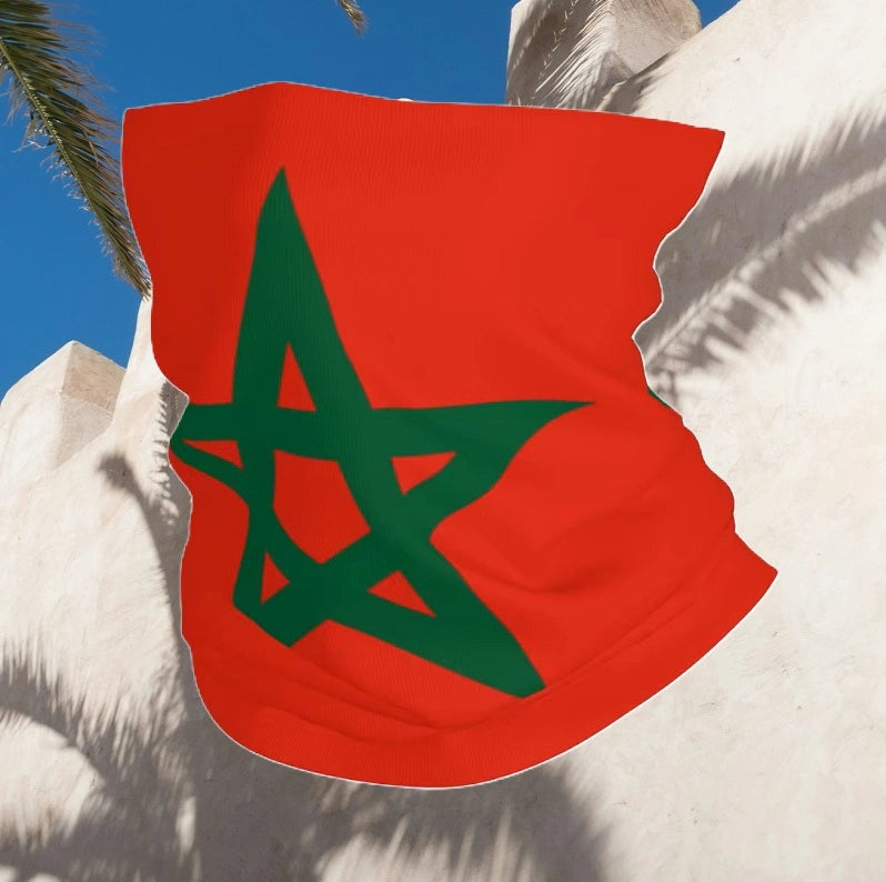 Cagoule Maroc rouge ornée d'une étoile verte flottant au vent sur un fond naturel. Accessoire polyvalent pouvant être utilisé comme tour de cou ou cache-visage.