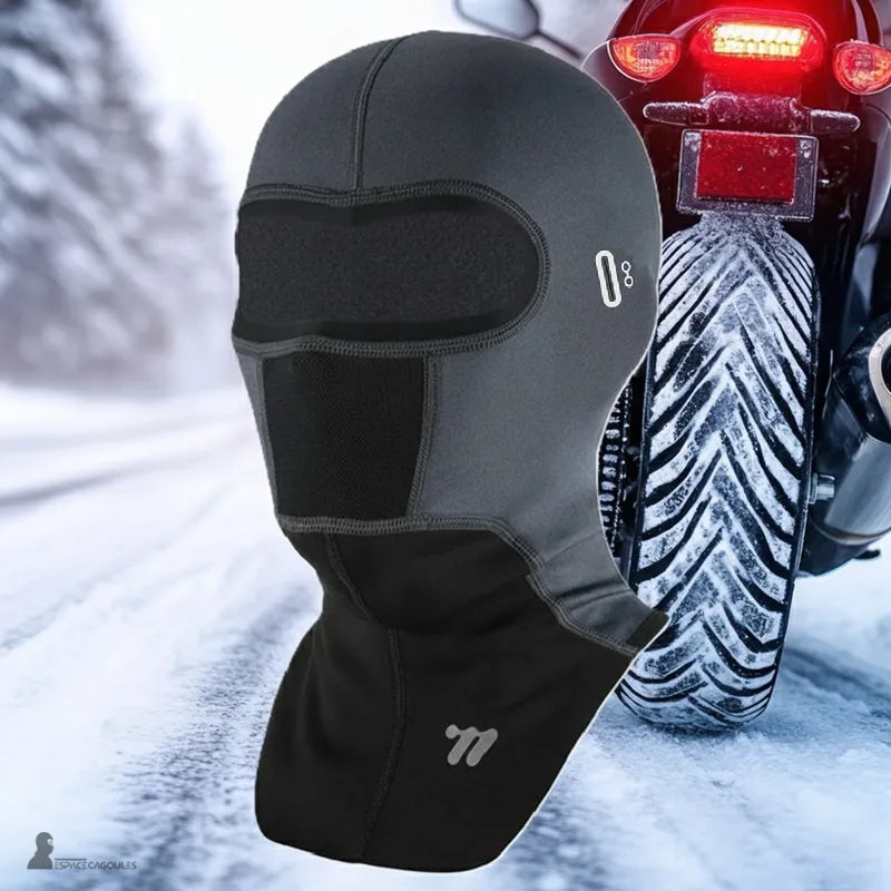 Cagoule moto hiver à plastron portée par un motard, textile technique avec doublure polaire, forme intégrale couvrante, vue portée en environnement hivernal sur route enneigée - Espace Cagoules