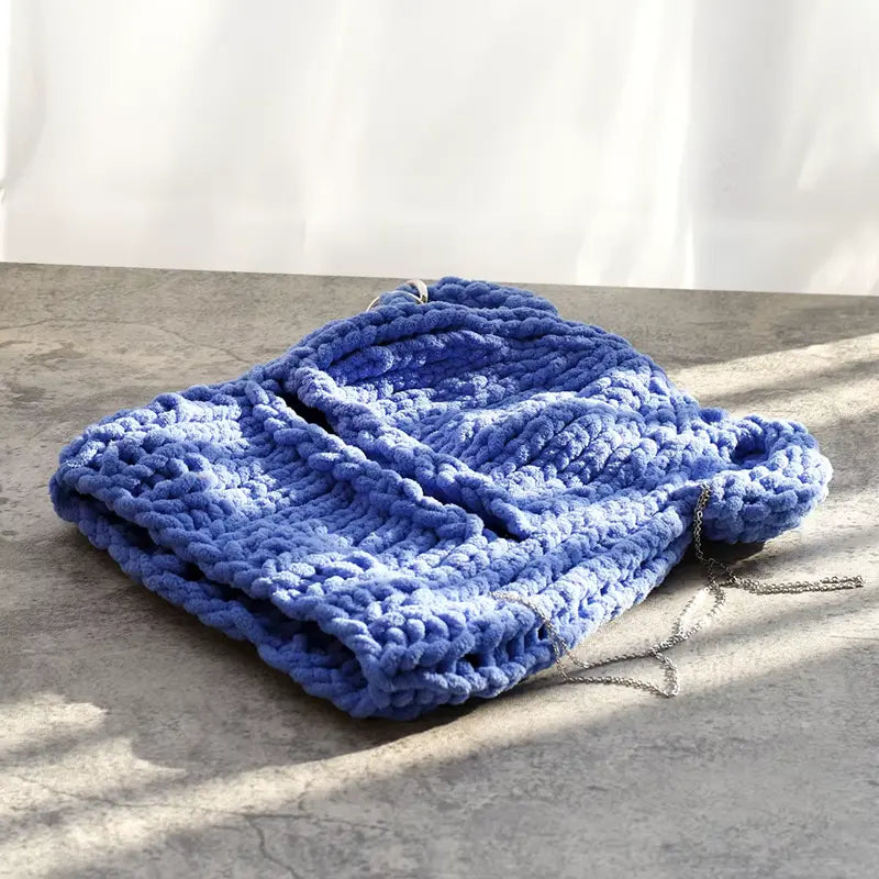 Sturmhaubenohren aus blauer Strickwolle, sorgfältig flach auf eine sonnige Oberfläche gelegt, ideal für den Winter.