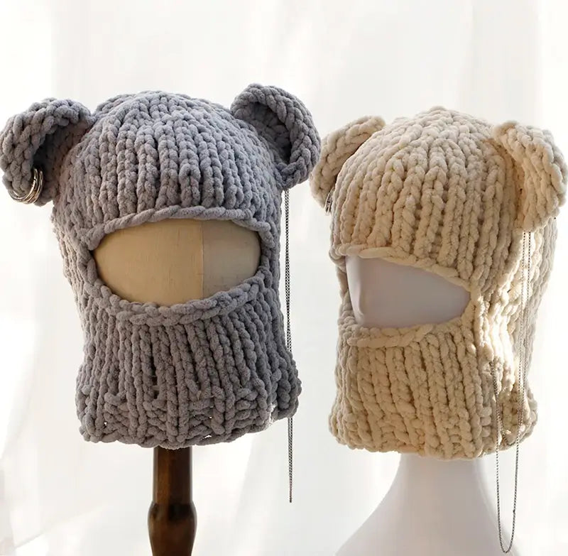 Zwei gestrickte Sturmhauben in den Ohren, eine graue und eine beige, die auf Schaufensterpuppen mit Gesichtsbedeckung dargestellt werden, perfekt für den Winter.