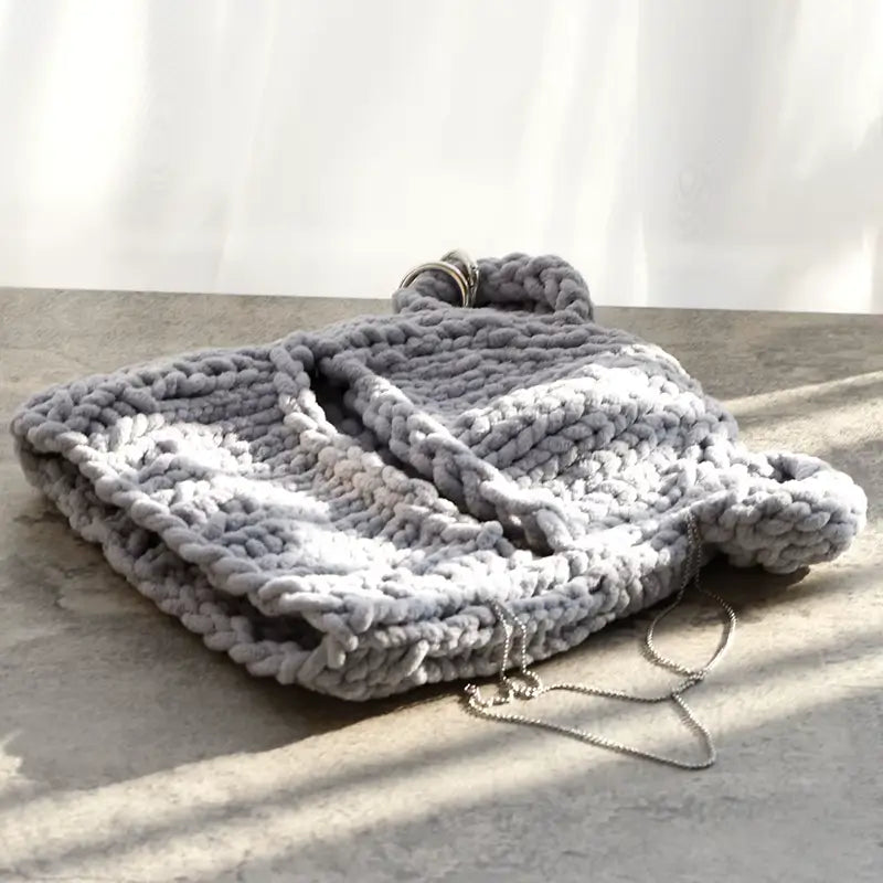 Kapuzenohren aus grauer Strickwolle, sorgfältig flach auf eine sonnige Oberfläche gelegt, ideal für den Winter.