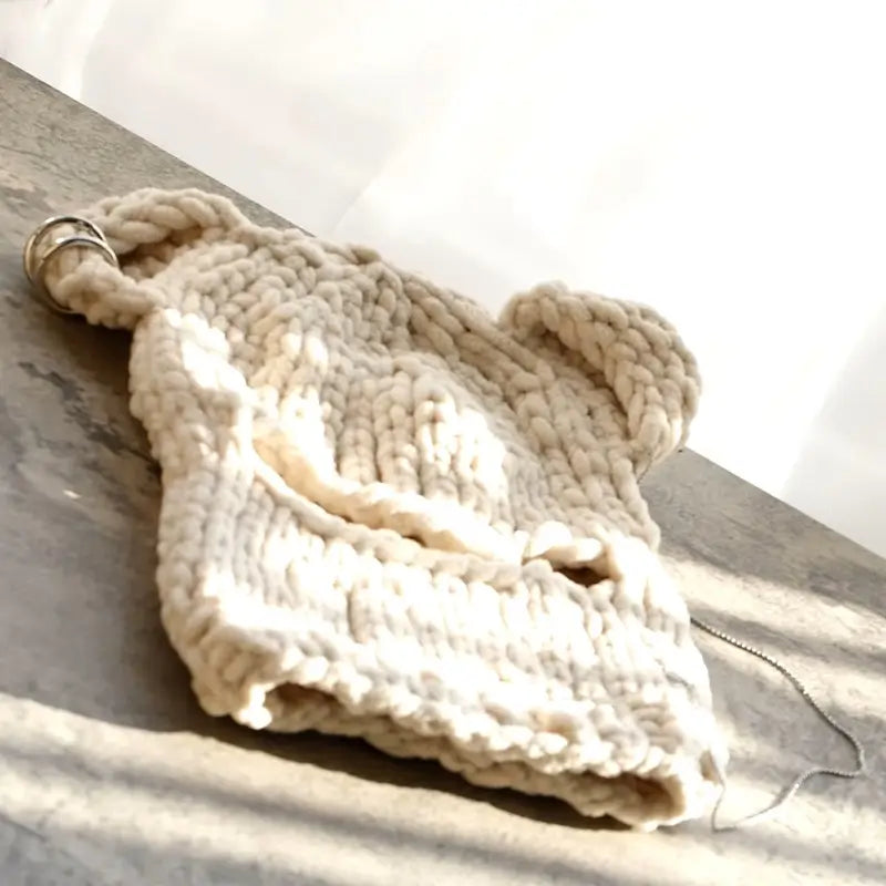 Sturmhaubenohren aus khakifarbener Strickwolle, sorgfältig flach auf eine sonnige Oberfläche gelegt, ideal für den Winter.