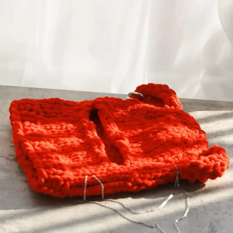 Sturmhaubenohren aus roter Strickwolle, sorgfältig flach auf eine sonnige Oberfläche gelegt, ideal für den Winter.