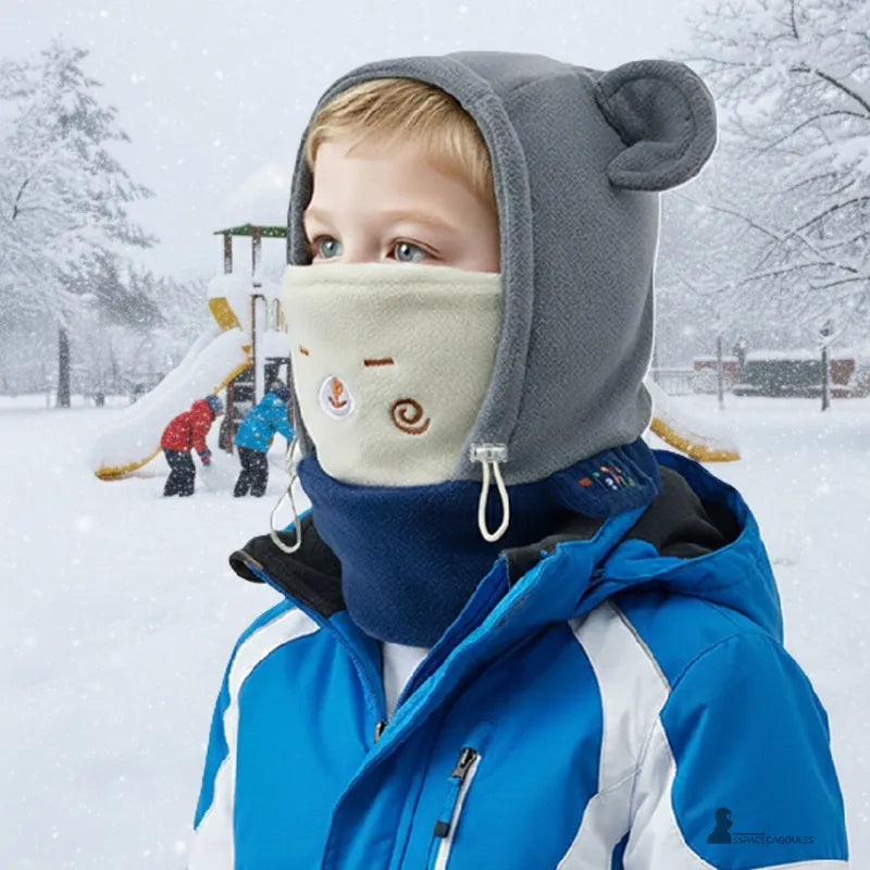 Cagoule polaire enfant 3 à 10 ans - garçon en extérieur sous la neige portant cagoule grise et cache-cou crème, arrière‑plan aire de jeu - Espace Cagoules