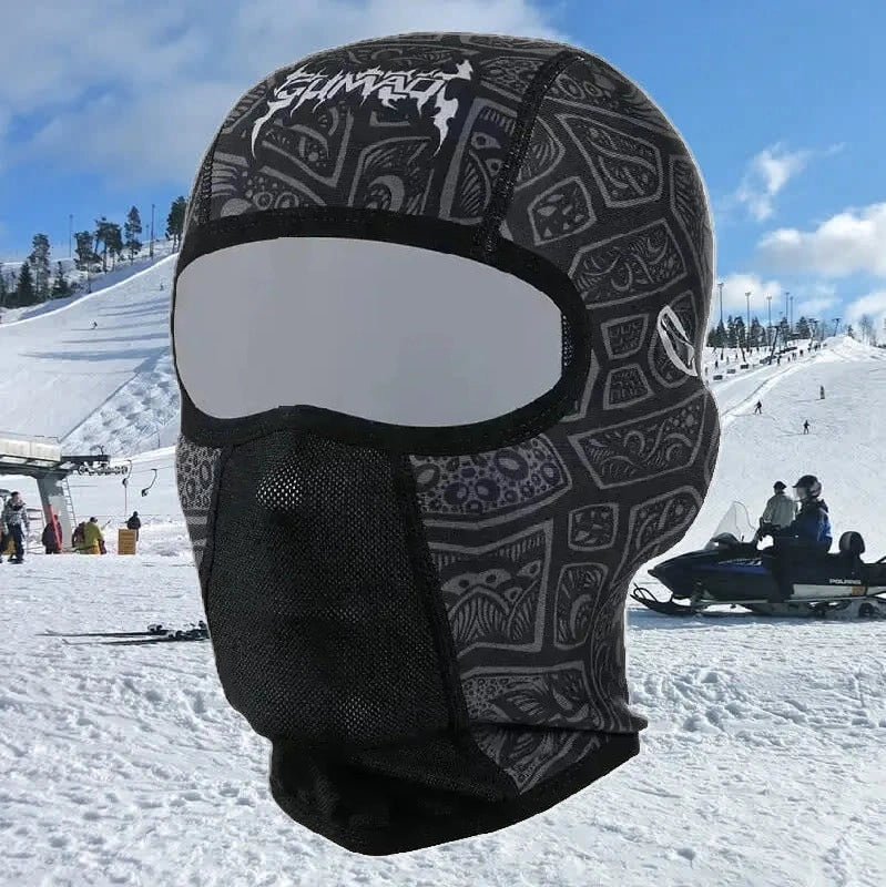 Cagoule pour Casque ski noire portée sur une piste enneigée, couvrant entièrement la tête et le cou pour un maintien au chaud.