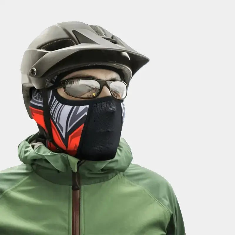 Person wearing a balaclava for riding a bike with a red and black colorful design, a breathable mask, and a gray helmet, ideal for outdoor activities and cold conditions.